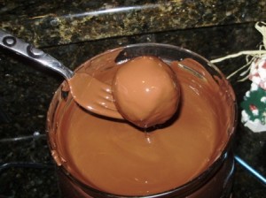 Maraschino Cake Bomb Balls Being Dipped In Melted Chocolate