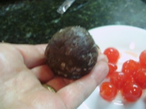 Chocolate coconut cake ball mixture wrapped around a maraschino cherry