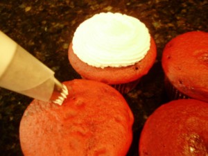 Red Velvet Cupcakes being iced with cake decorators icing
