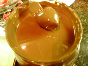 Heart shaped cake ball being dipped in melted chocolate