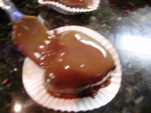 Heart shaped cake ball cover in chocolate being placed on mini cupcake liner