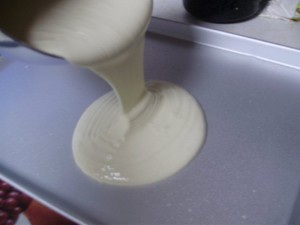 Half Sheet Cake with Batter Being Poured Into It